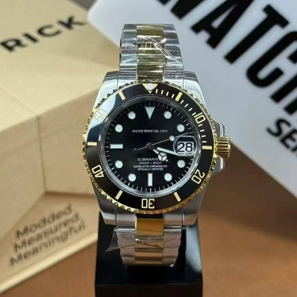 Gold and silver Seiko mod dive watch with black bezel and date window on display stand