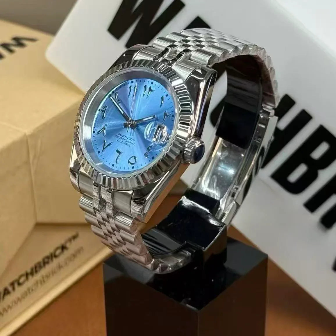 Stainless steel automatic watch with textured blue Arabic dial on display stand
