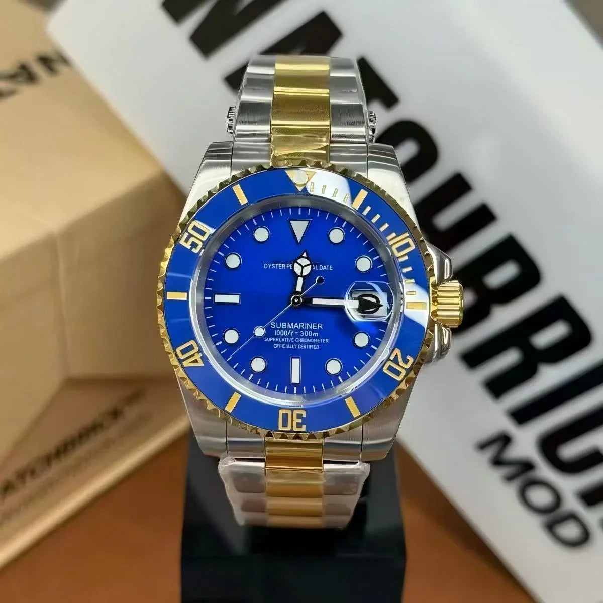 Blue and gold automatic dive watch with stainless steel bracelet on display stand