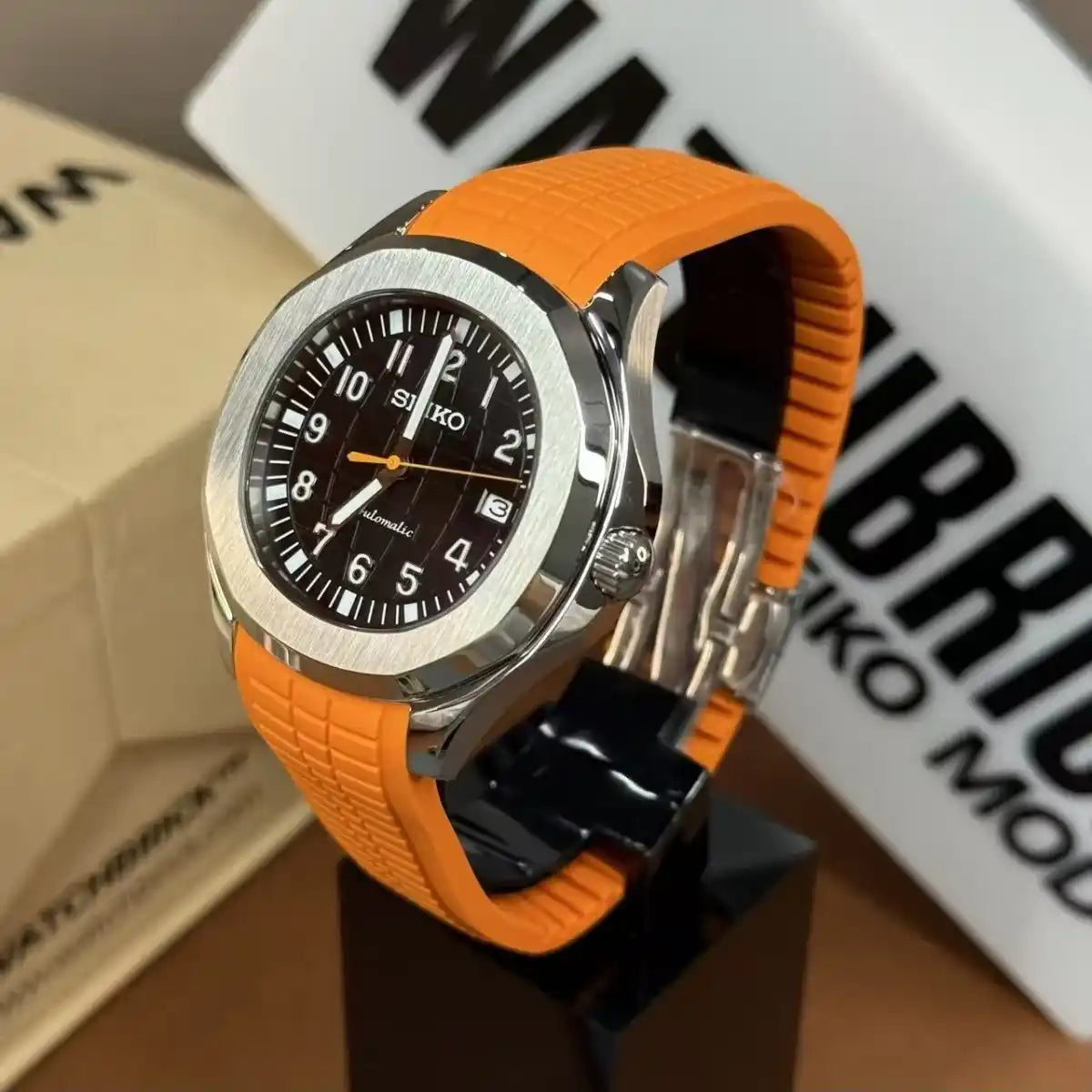 Seiko mod watch with orange rubber strap, black dial, silver bezel, and date display