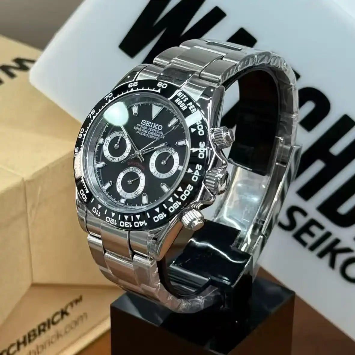 Stainless steel Seiko mod chronograph watch with black dial and tachymeter bezel on display.