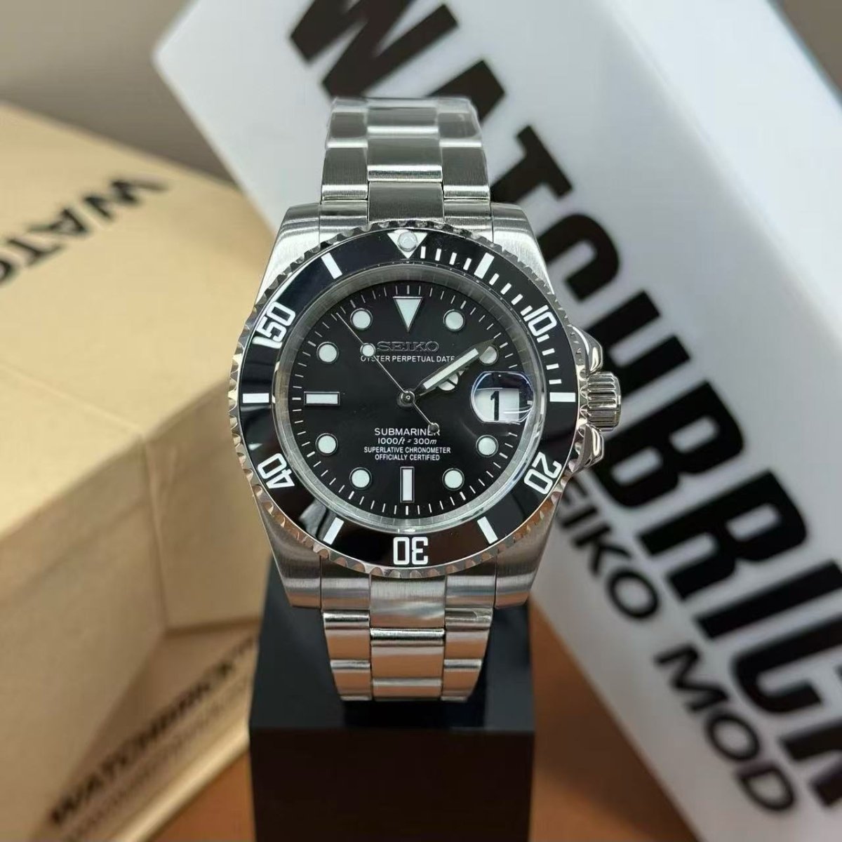 Seiko mod dive watch with black bezel, black dial, and stainless steel bracelet on display