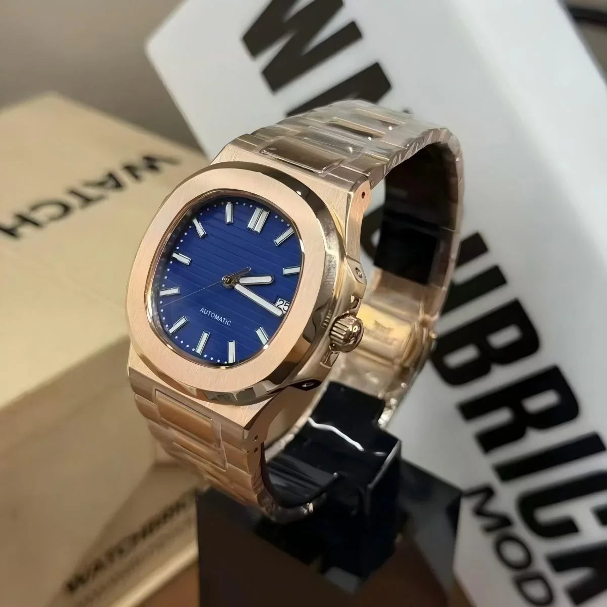 Gold tone automatic watch with a blue dial and date display on a metal bracelet
