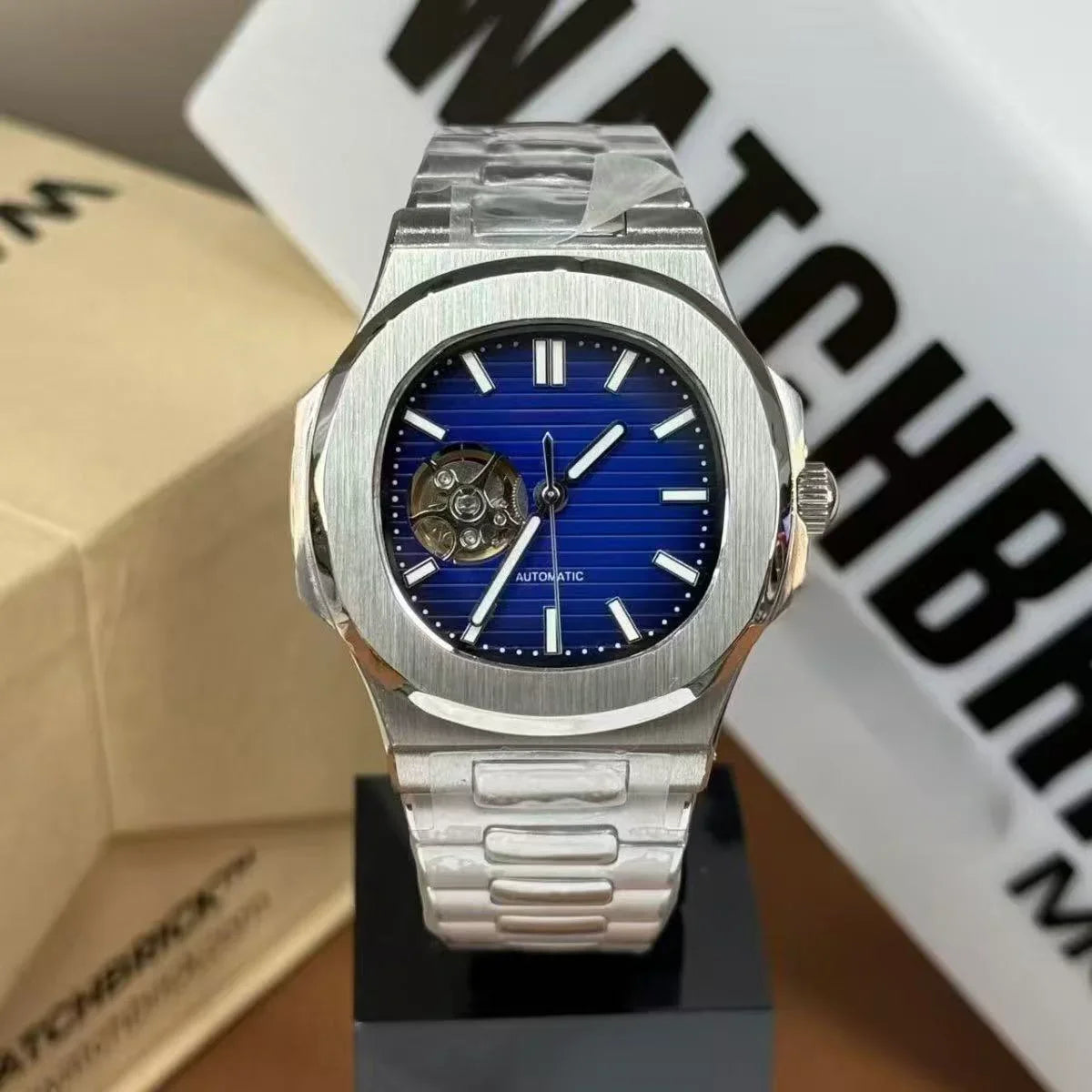 Silver automatic watch with blue dial, open-heart design, and stainless steel bracelet
