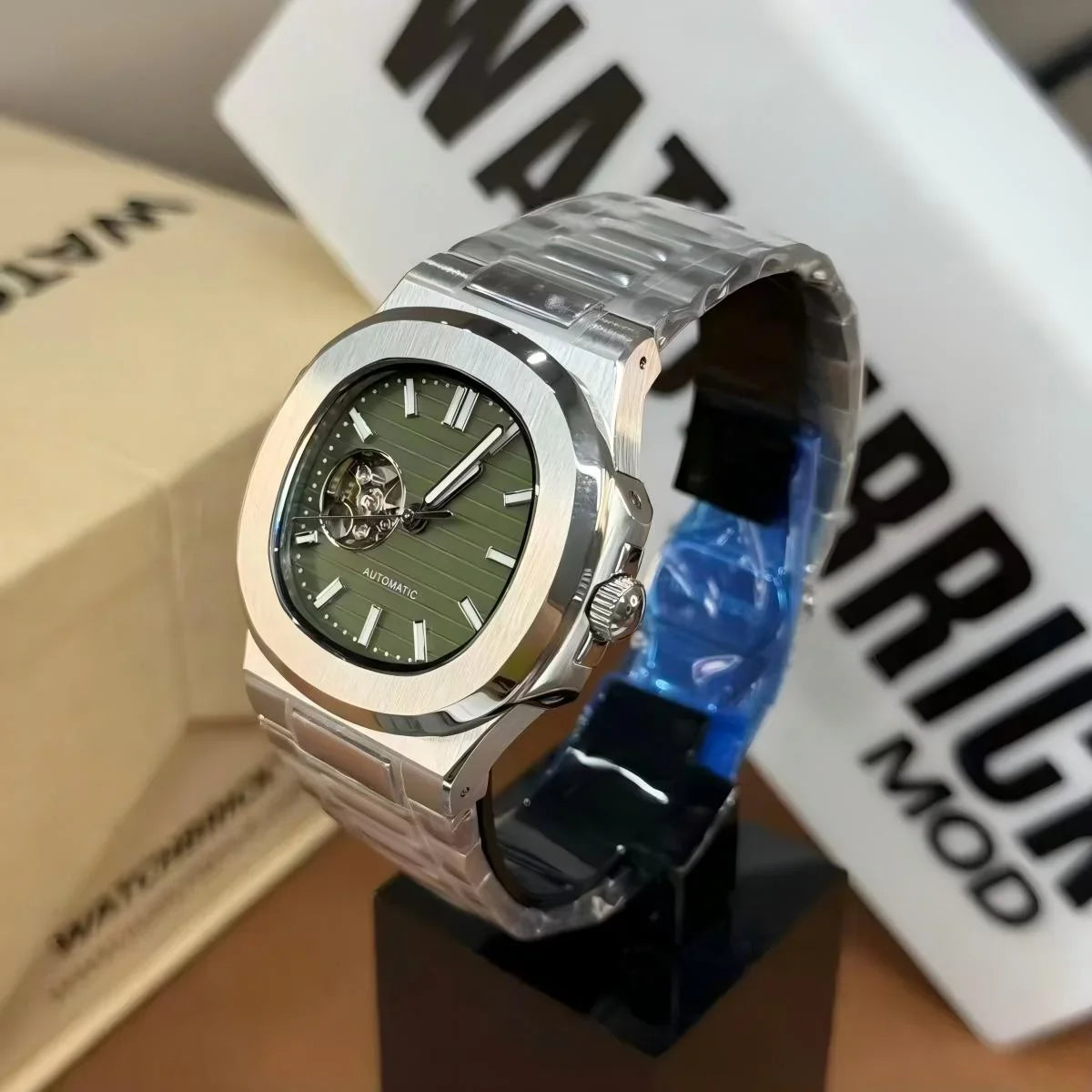 Stainless steel automatic watch with green open-heart dial on display stand