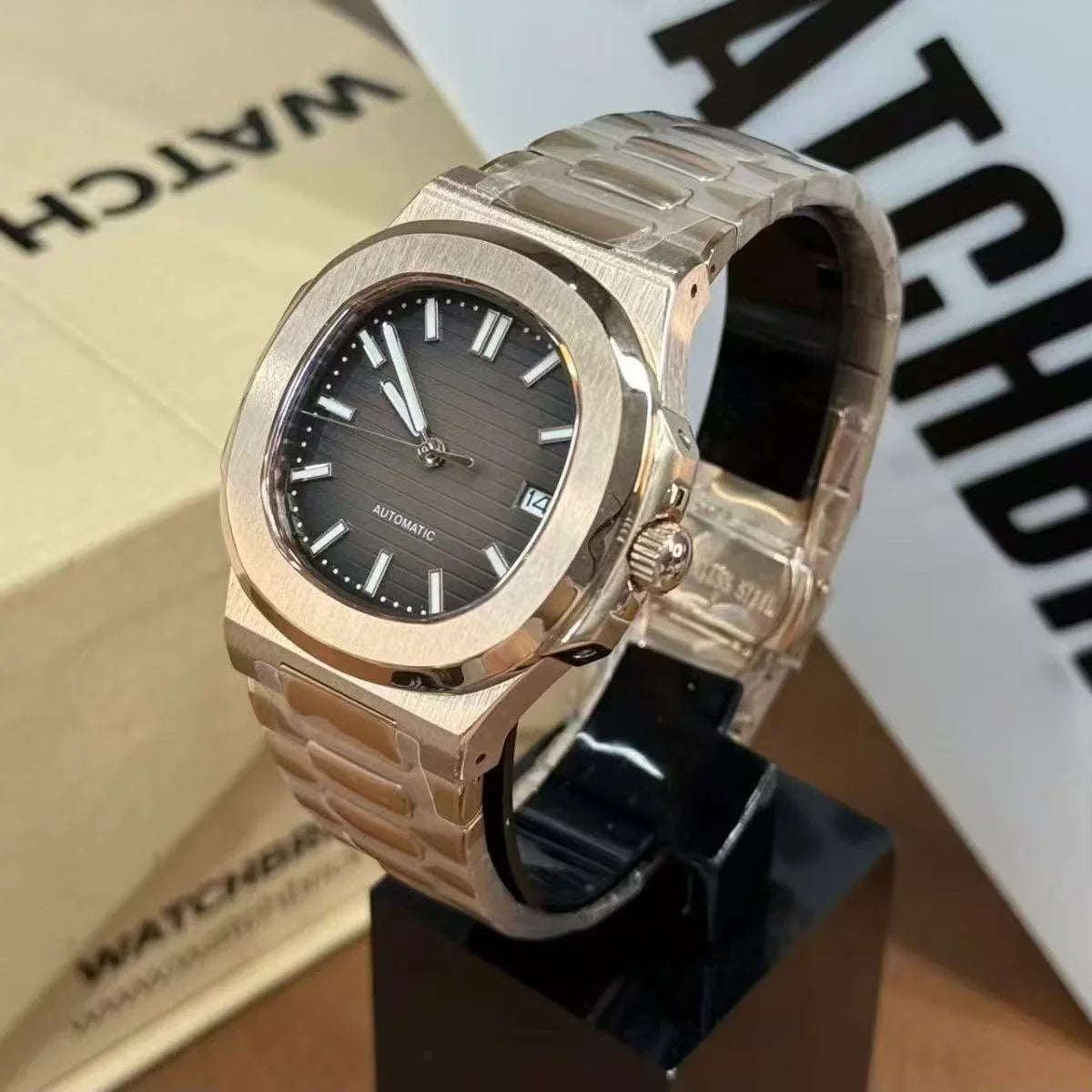 Luxury stainless steel mod watch with gray dial, date display, and automatic movement on stand