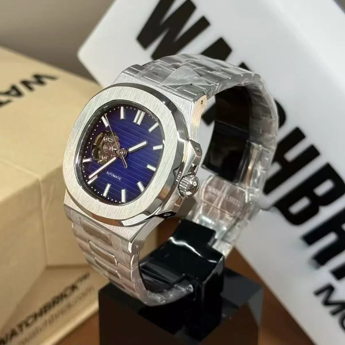 Stainless steel automatic watch with blue dial and open-heart design on display stand