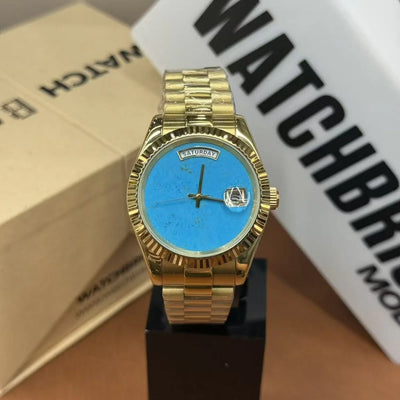 Gold wristwatch with turquoise dial and day-date display on a stand