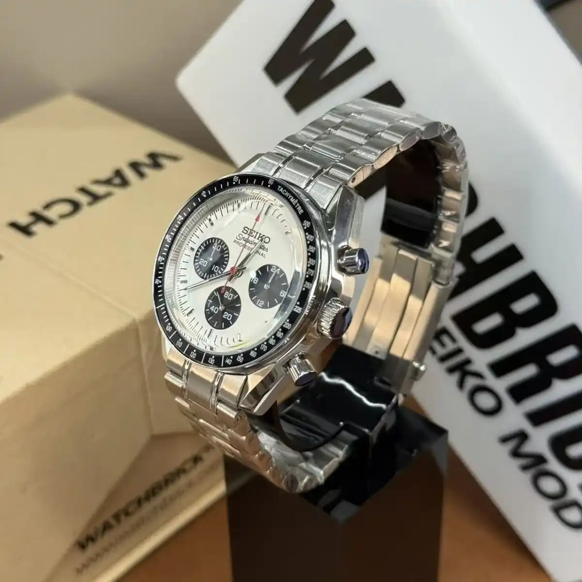 Seiko mod chronograph watch with panda dial, stainless steel band, and black bezel on display.