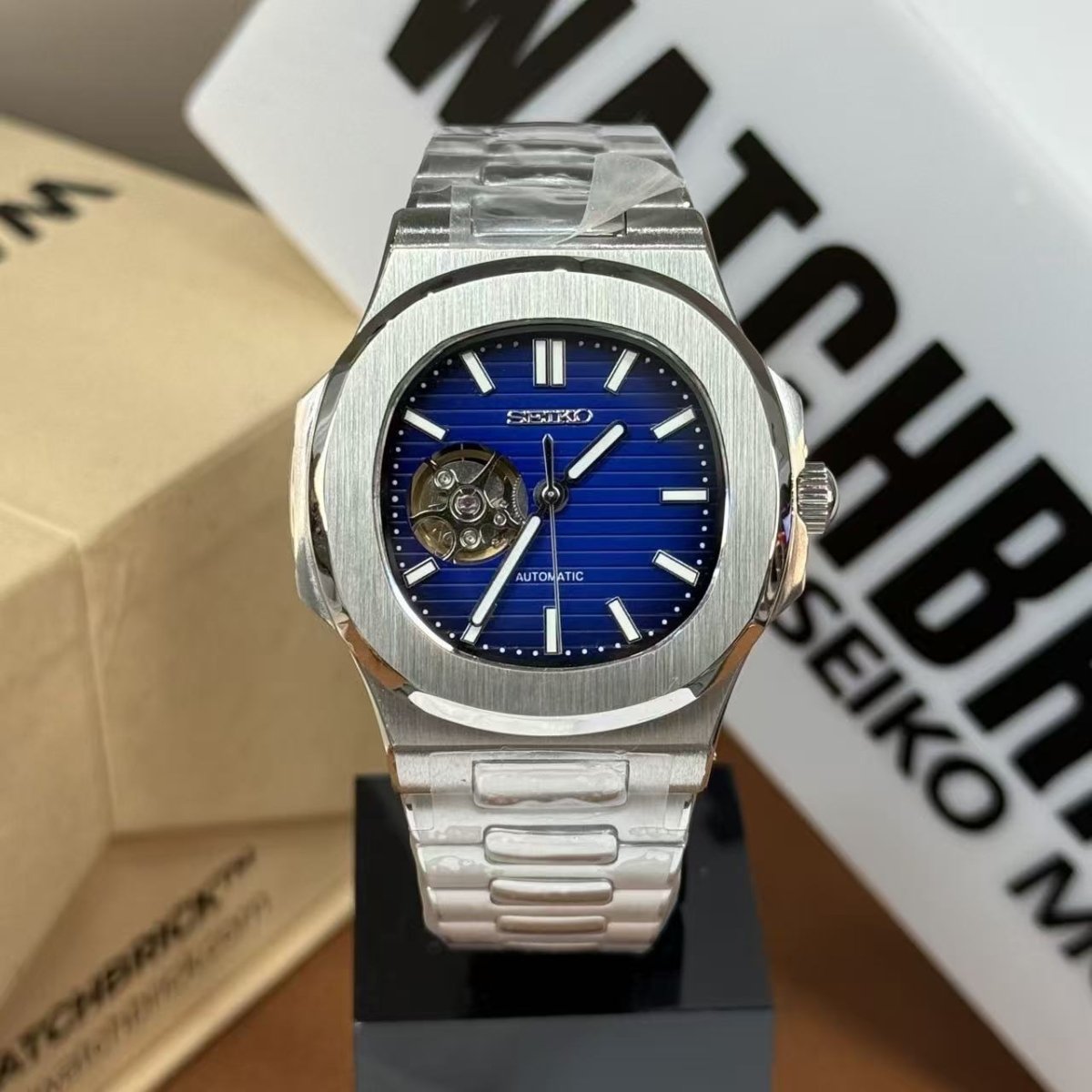 Seiko mod watch with open-heart dark blue dial and stainless steel bracelet on display.
