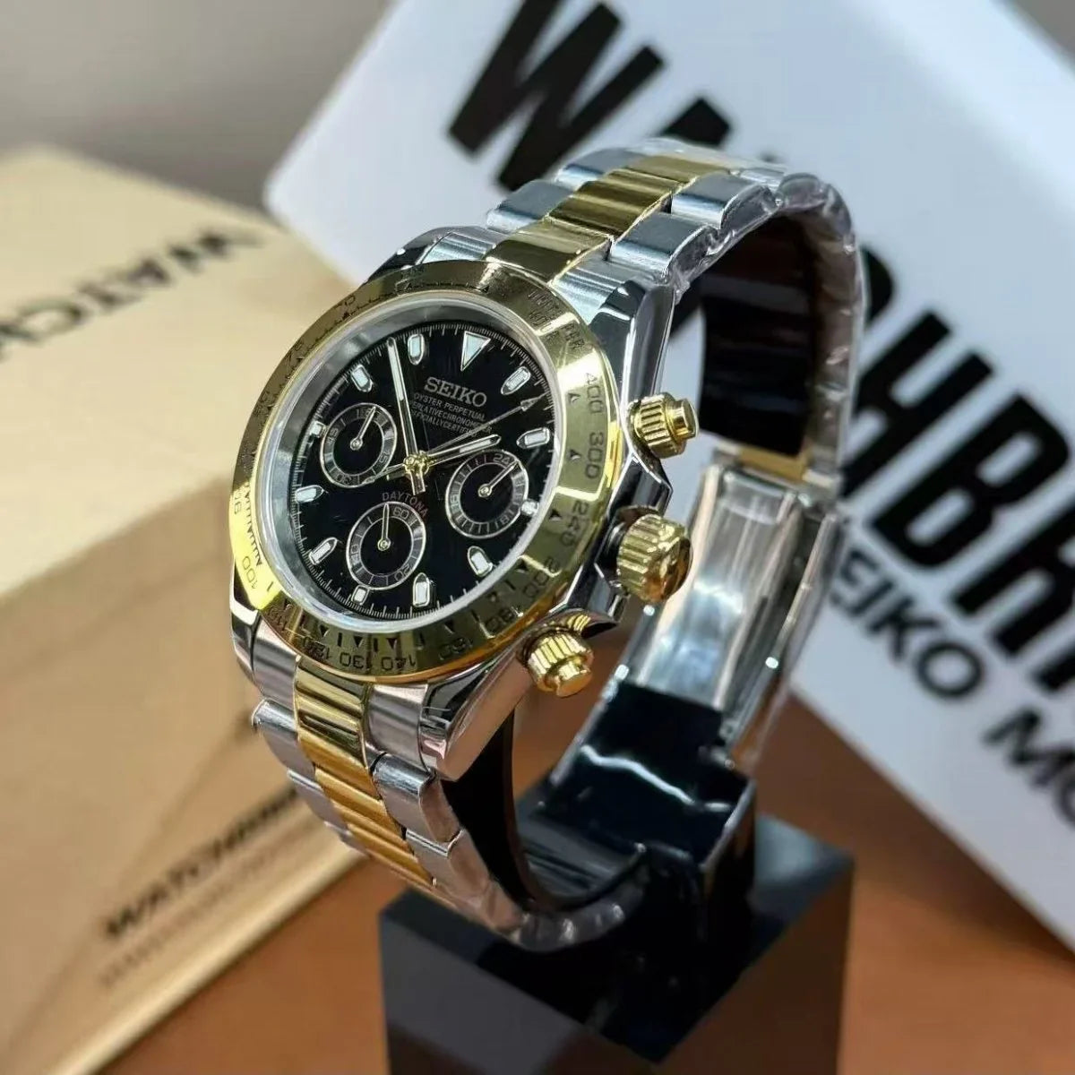 Two-tone Seiko chronograph watch with black dial, gold bezel, and stainless steel bracelet